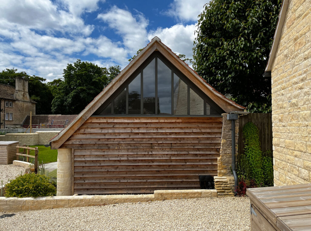 A barn conversion with a contempory window at The Farmyard in Grittleton, Wiltshire